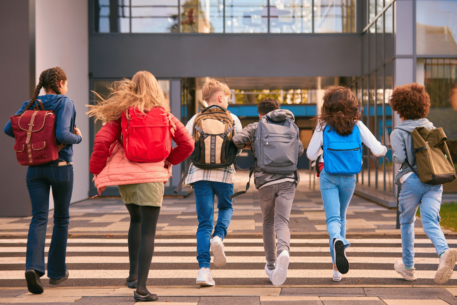 Ragazzi di Scuola secondaria di primo grado di spalle che corrono verso scuola