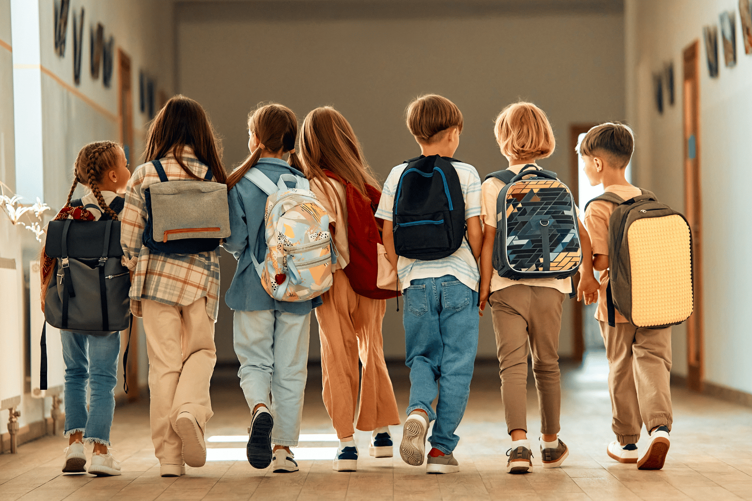 Bambini di Scuola primaria di spalle che camminano nel corridoio della scuola