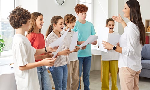 cinque ragazzi e ragazze che cantano in coro con insegnante