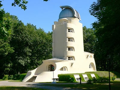 Torre di Potsdam: Un edificio bianco dalle forme arrotondate, con una cupola in cima, circondato da alberi e vegetazione.