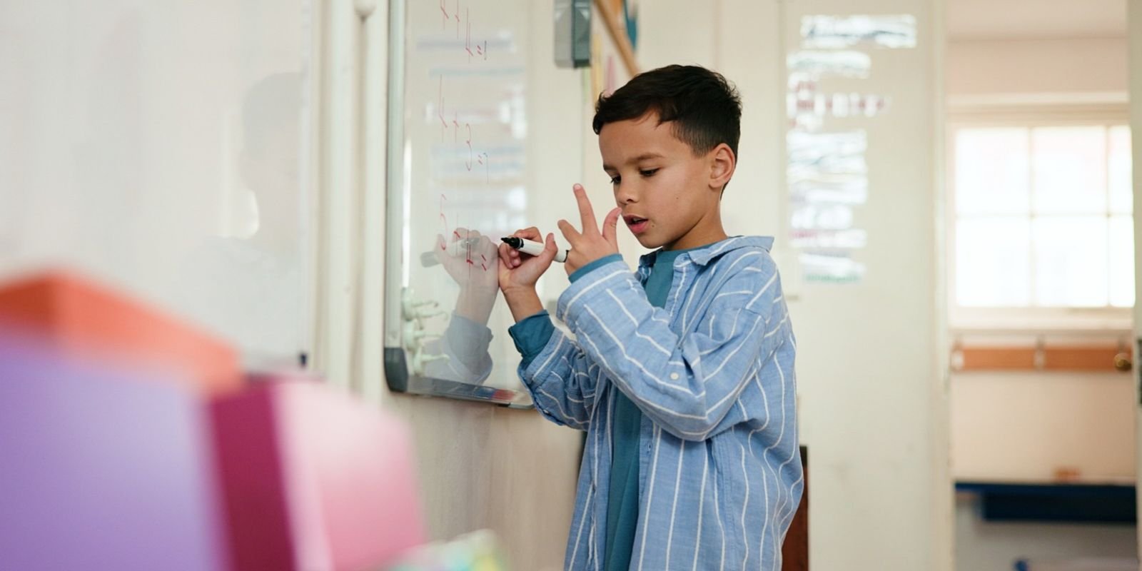 Bambino che scrive su una lavagna bianca e risolve un problema di matematica
