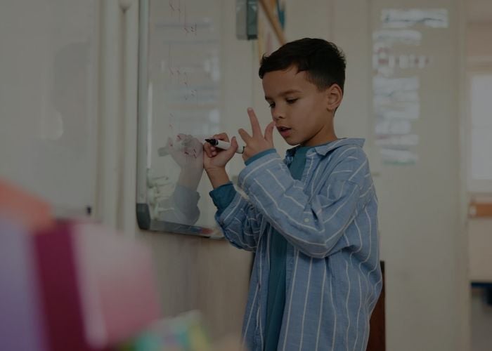 Bambino che scrive su una lavagna bianca e risolve un problema di matematica